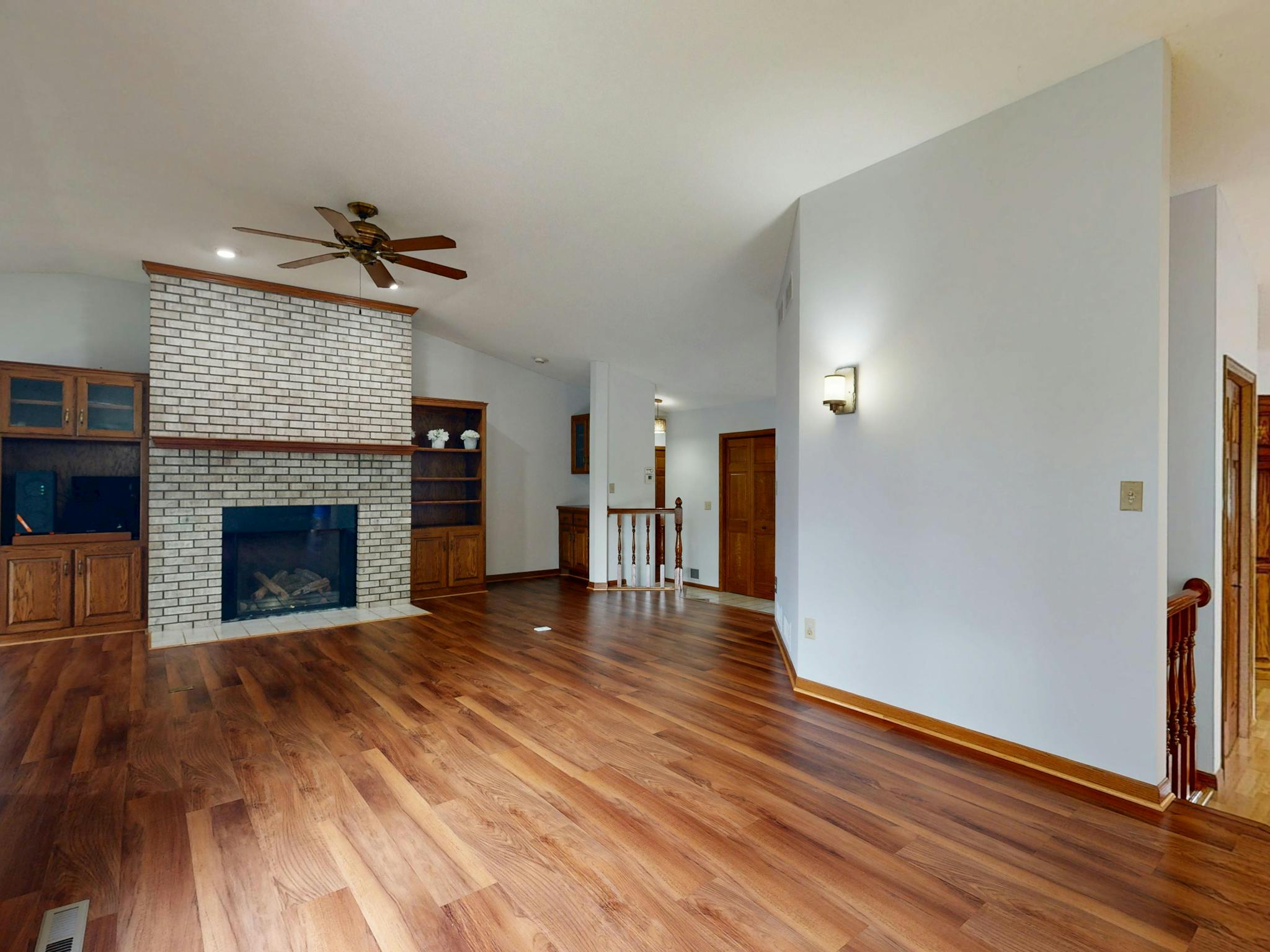 Bright and spacious living room featuring a brick fireplace, hardwood floors, and built-in cabinets.
