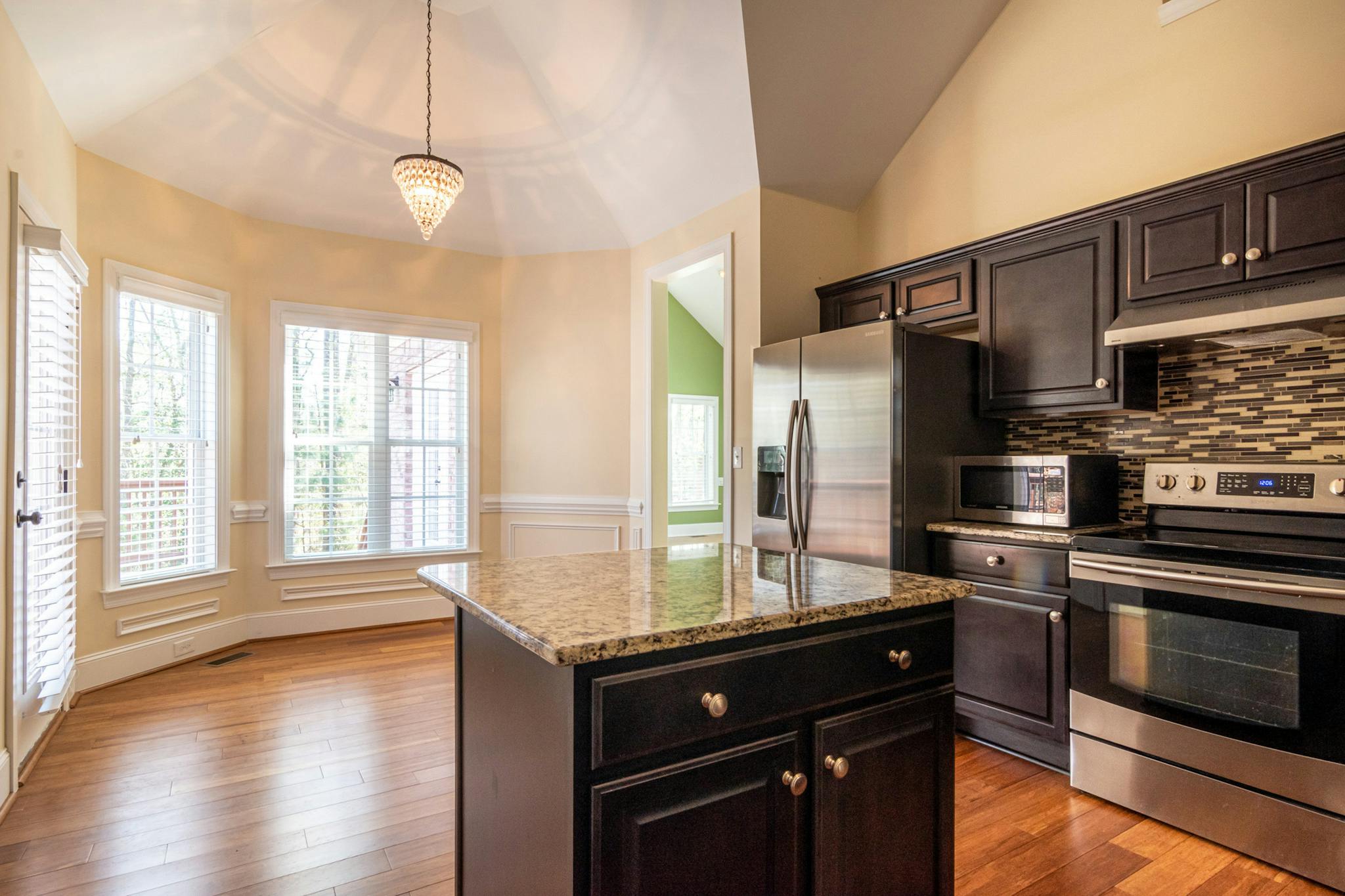 Bright, contemporary kitchen interior featuring marble countertops, hardwood floors, and ample natural light.